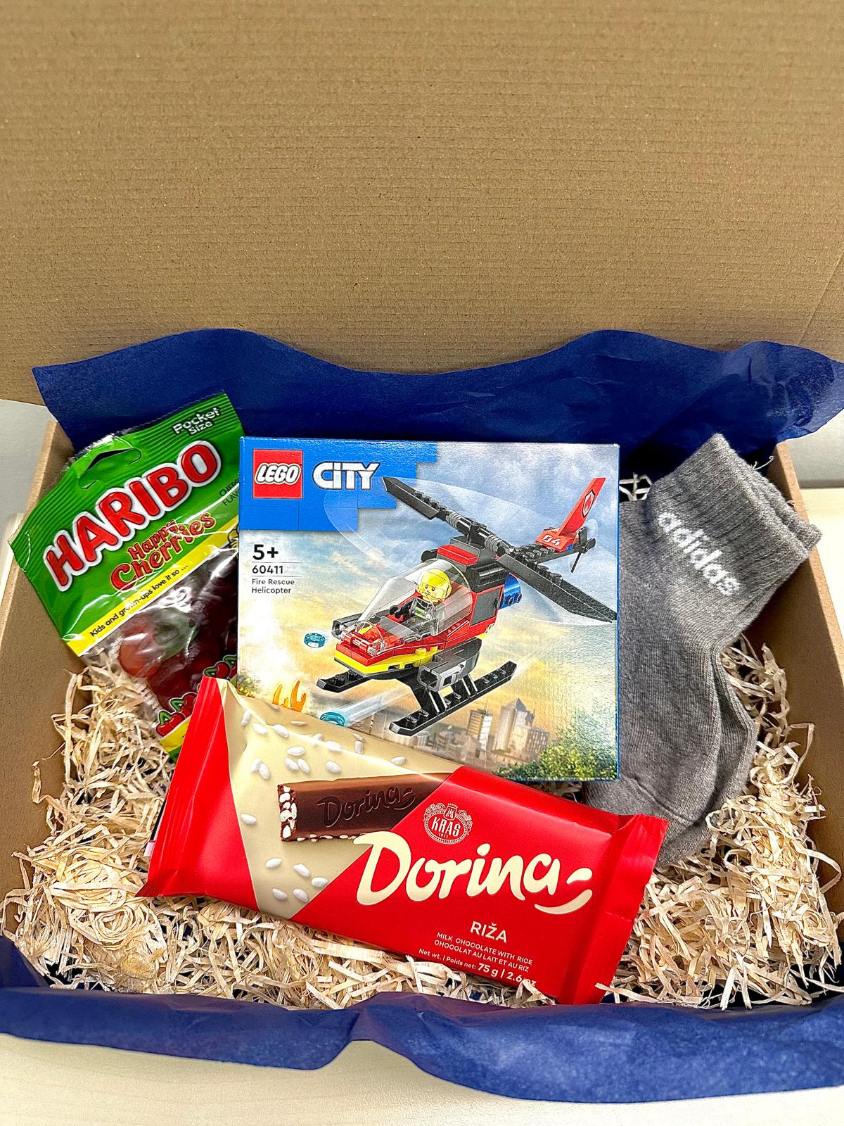 A gift package with a Lego City theme and Dorina chocolates, includes themed snacks, adidas socks, and products for fans of puzzles and sweets.